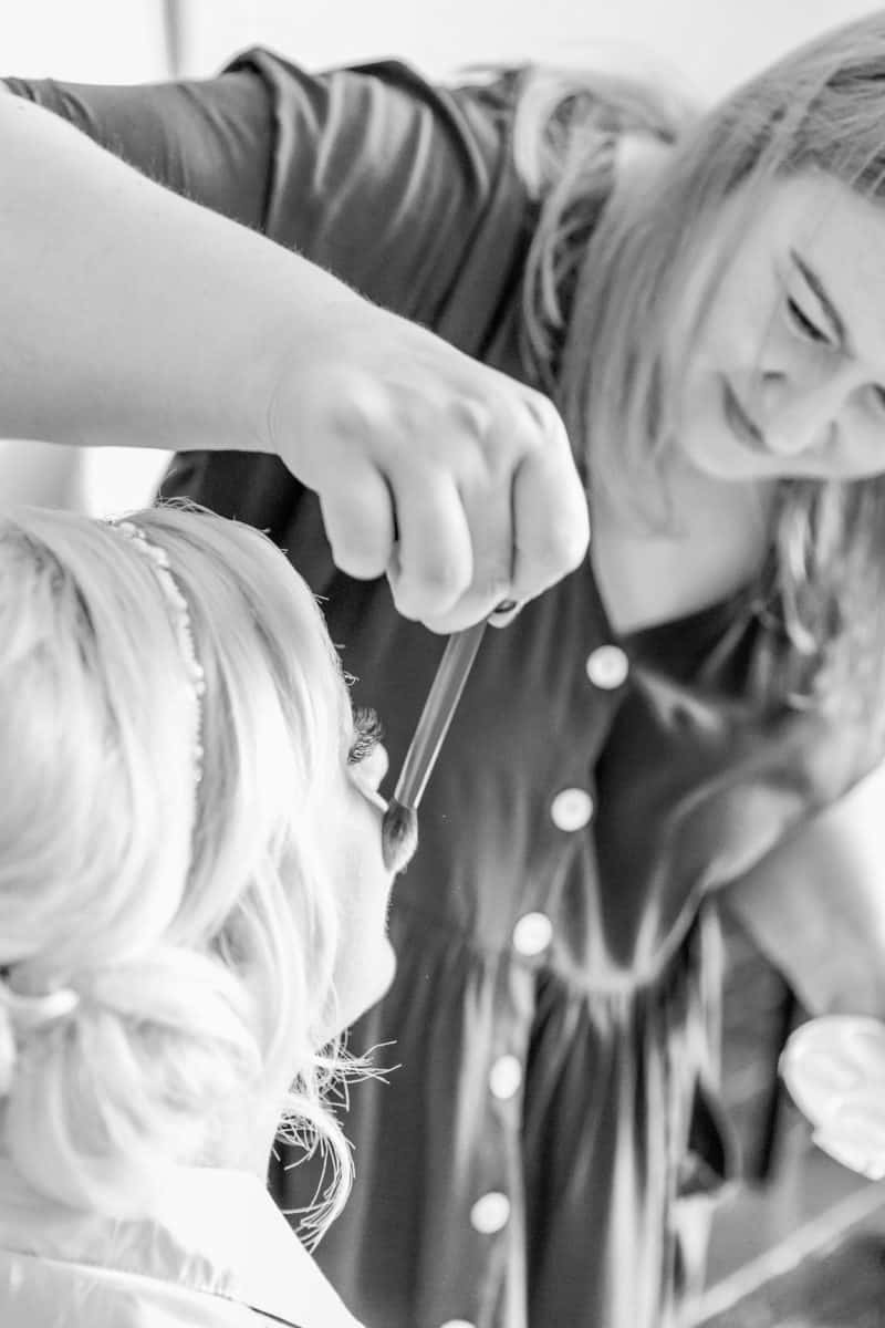 Professional hair and makeup artist applies blusher to a bride