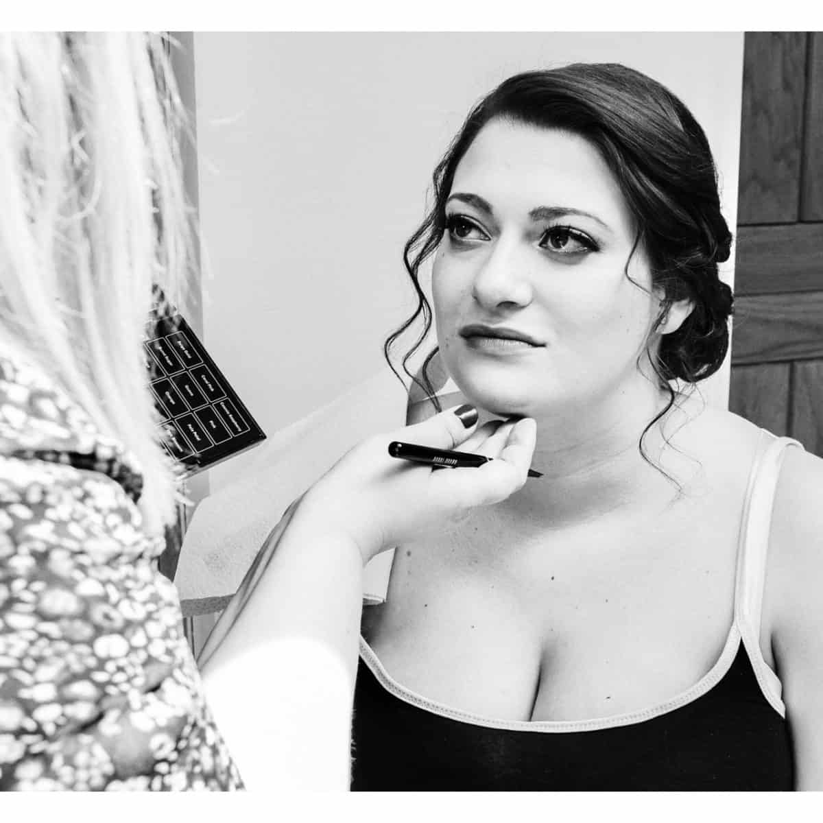 Expert hair and makeup artist applies makeup to a bride on the morning of her wedding